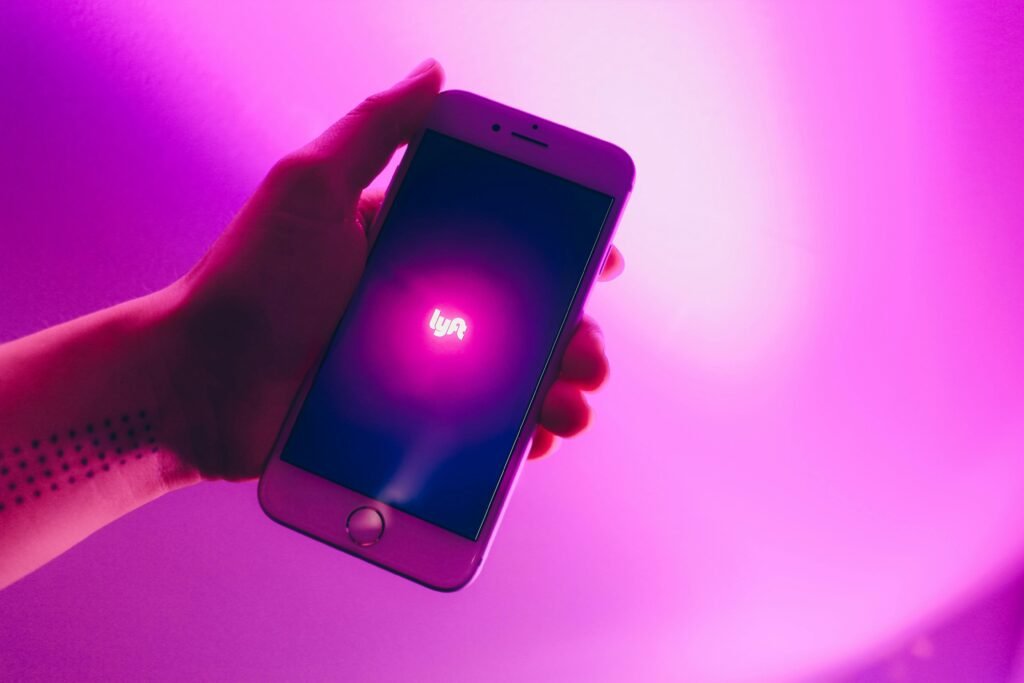 pexels-photo-2228574-2228574 A hand holding a smartphone displaying the Lyft ridesharing app with a vivid pink background.